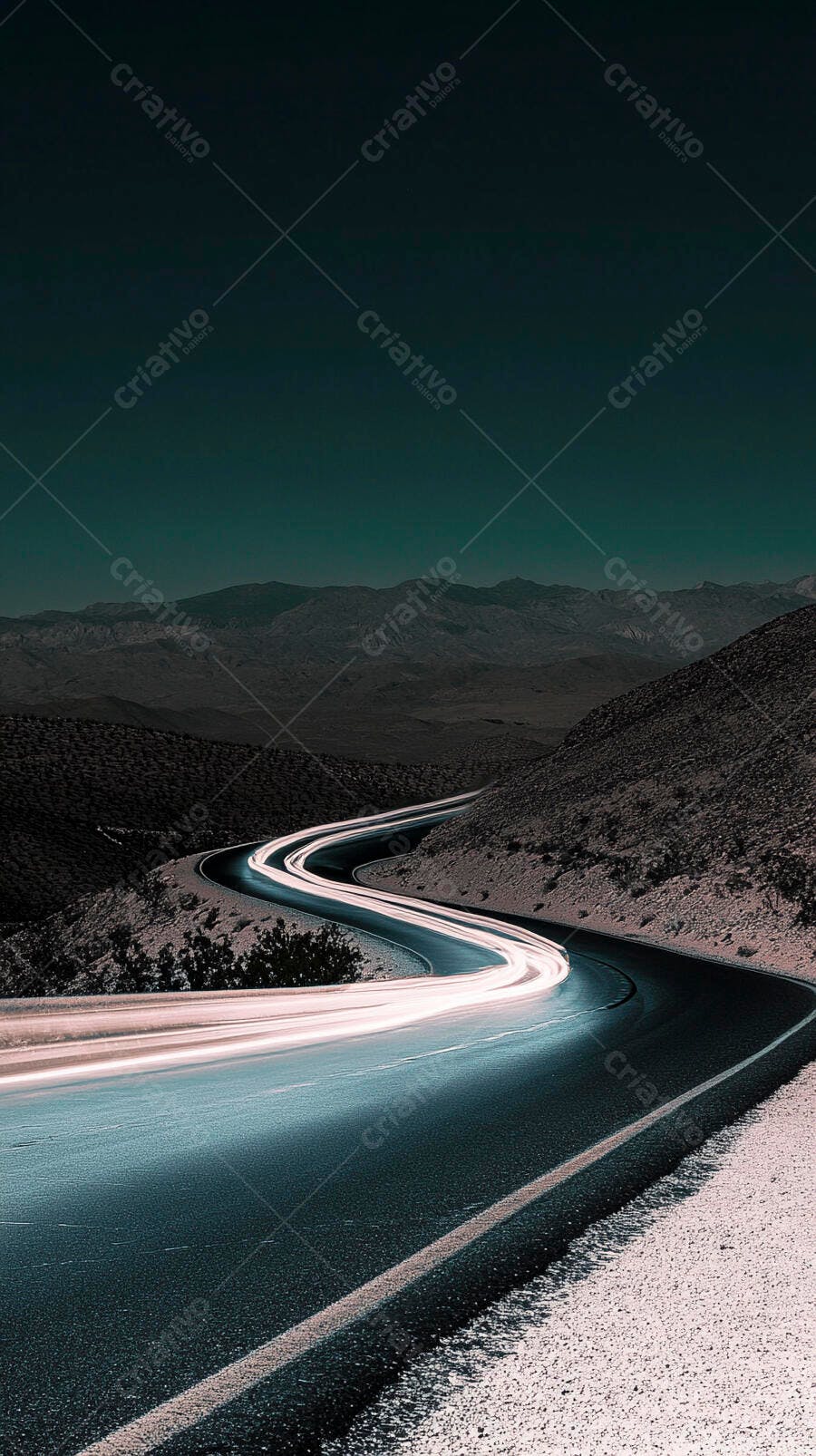 Estrada sinuosa no deserto à noite com rastros de luz de veículos