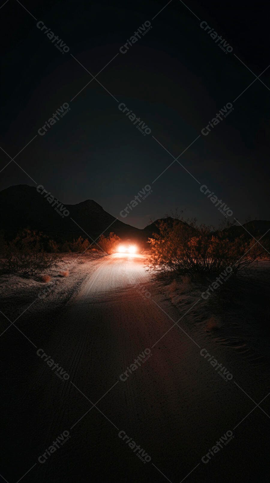 Carro com faróis acesos em estrada de terra no deserto à noite