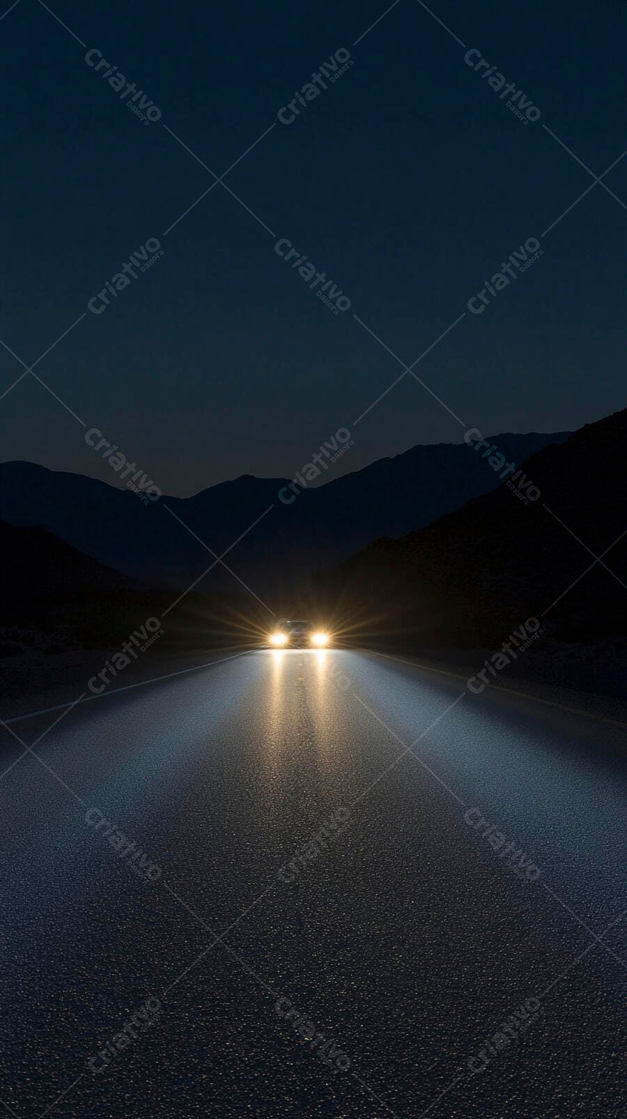 Carro branco dirigindo em estrada escura à noite com faróis acesos e montanhas distantes