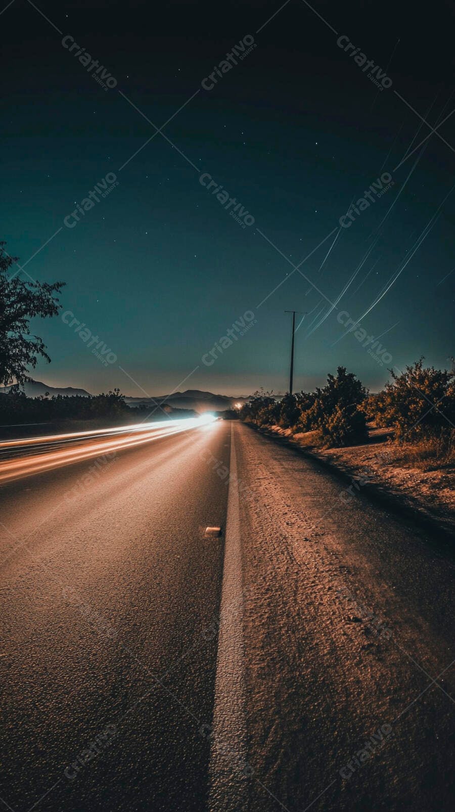 Estrada noturna com rastros de luz de carros em movimento sob céu estrelado