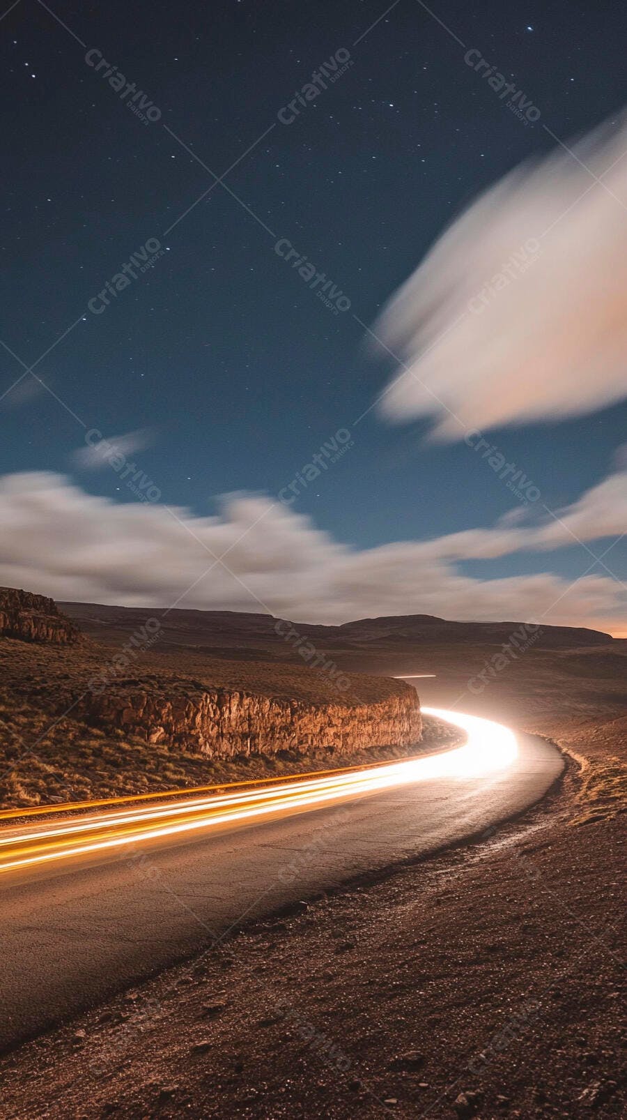 Estrada noturna com rastros de luzes em montanhas sob céu estrelado