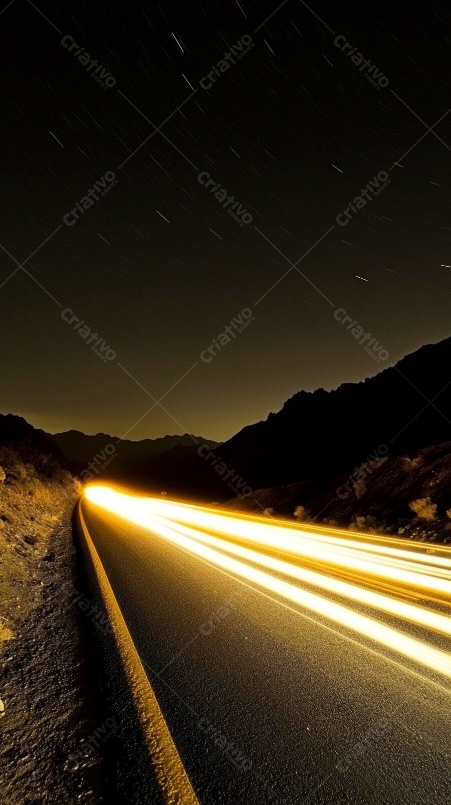 Rodovia noturna com rastros de luz dourados em montanhas escuras