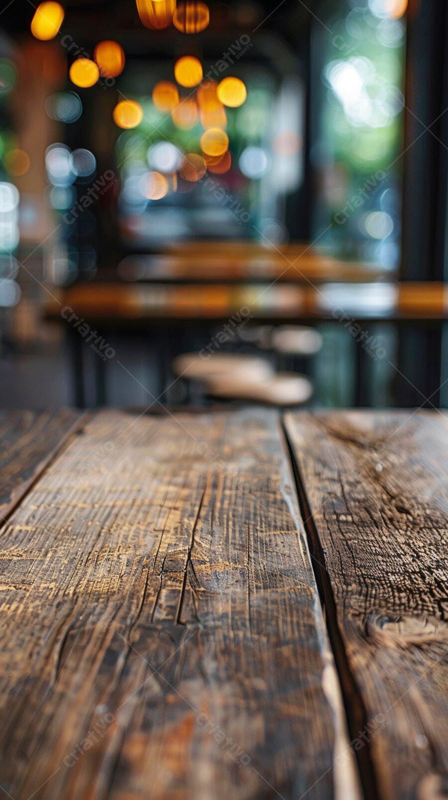 Mesa de madeira rústica em primeiro plano com luzes douradas de café desfocadas