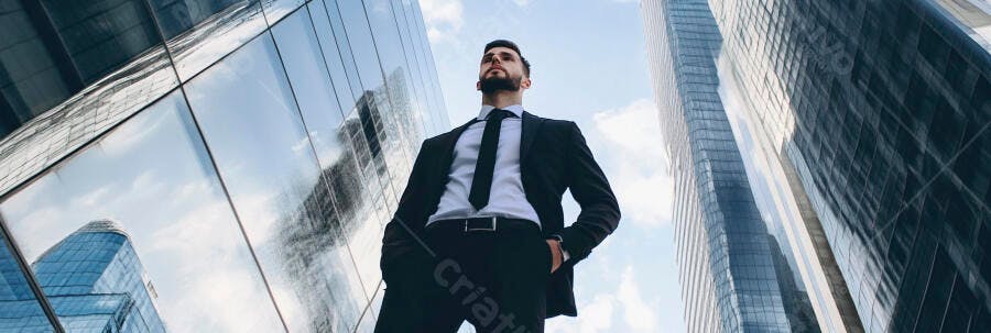 Homem de negócios barbudo em terno preto com edifícios espelhados urbanos ao fundo