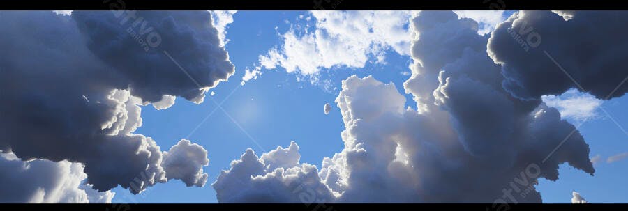 Nuvens volumosas e escuras contra céu azul com raios de sol
