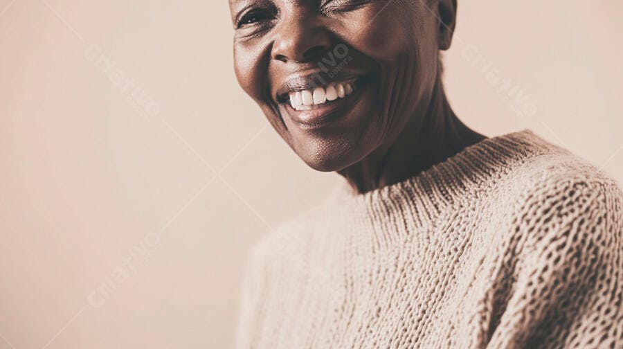 Mulher negra idosa sorrindo feliz com blusa de tricô bege em fundo claro
