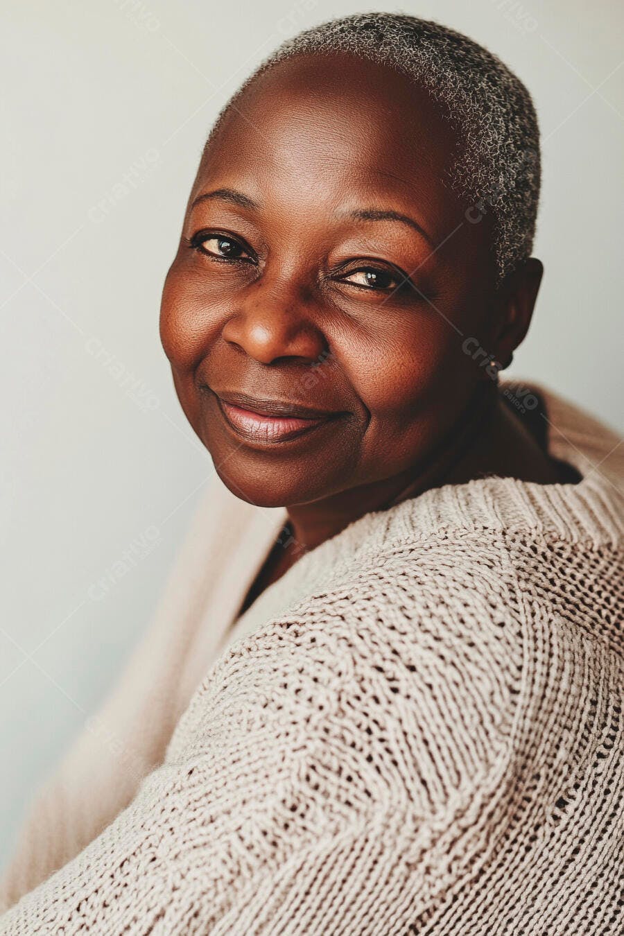 Mulher negra idosa sorrindo com cabelo grisalho e suéter de tricô bege