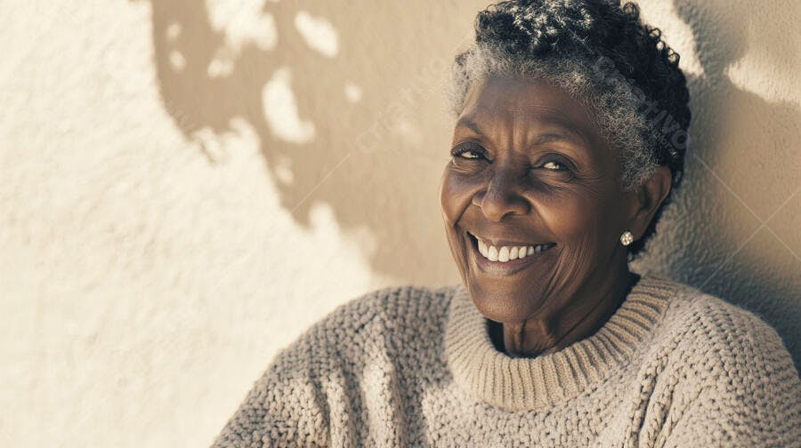 Mulher idosa negra feliz sorrindo em suéter bege sob luz solar