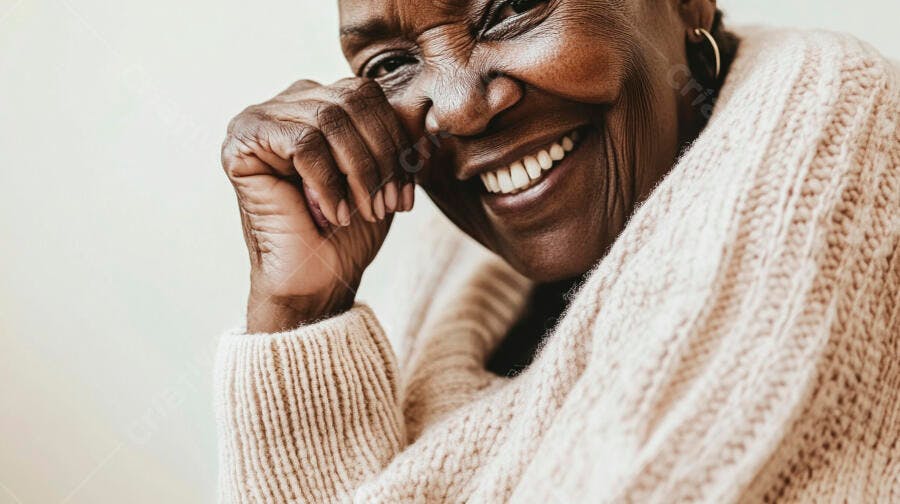 Mulher negra idosa sorrindo feliz usando suéter bege em close-up