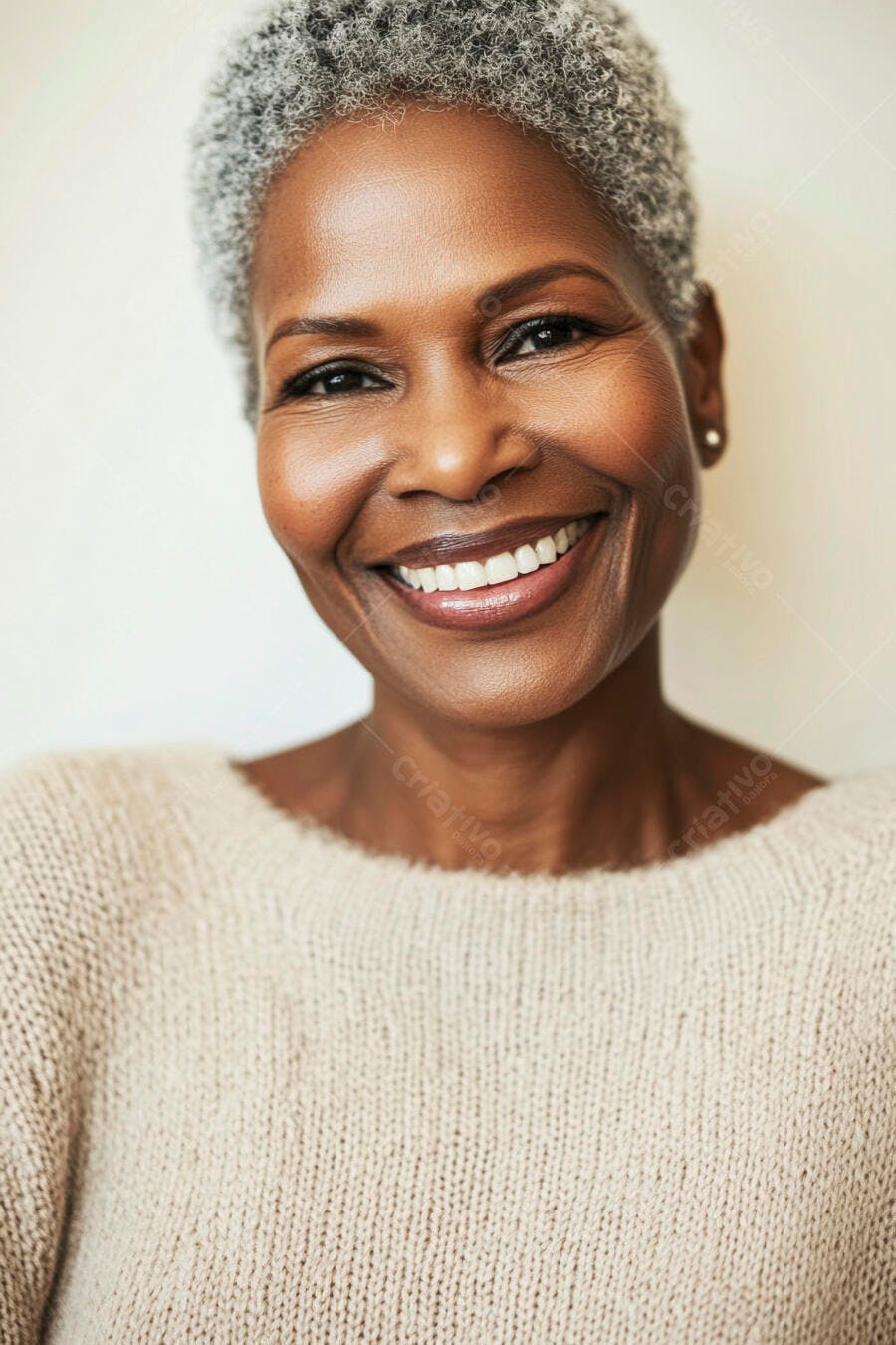 Mulher negra sorrindo com cabelo grisalho e suéter bege claro