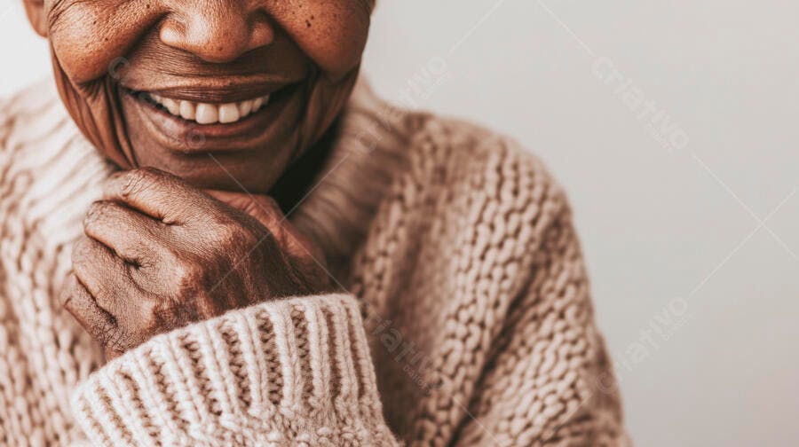 Mulher idosa negra sorrindo feliz com suéter bege e mão no queixo