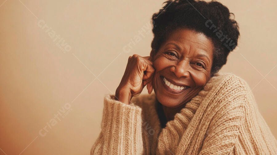 Mulher negra idosa com sorriso radiante e suéter bege em fundo neutro