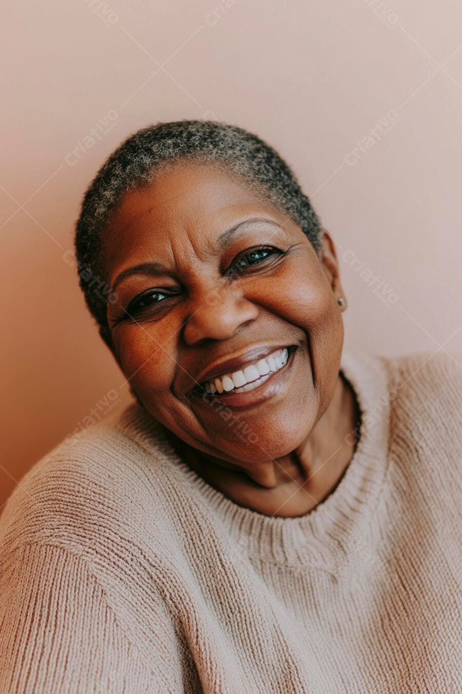 Mulher negra idosa sorrindo feliz com suéter bege em fundo pêssego