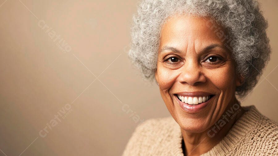 Mulher idosa negra sorrindo feliz com cabelo grisalho e suéter bege em fundo neutro