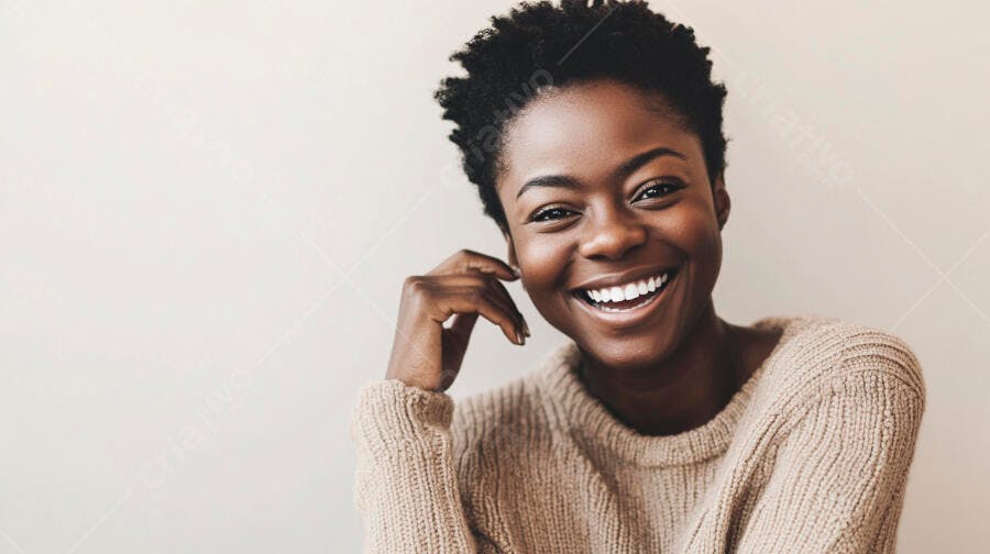 Mulher negra feliz com suéter bege sorrindo amplamente em fundo claro
