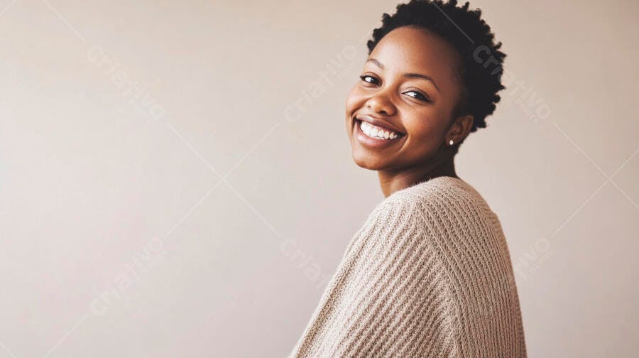 Mulher negra jovem sorrindo com suéter bege fundo claro