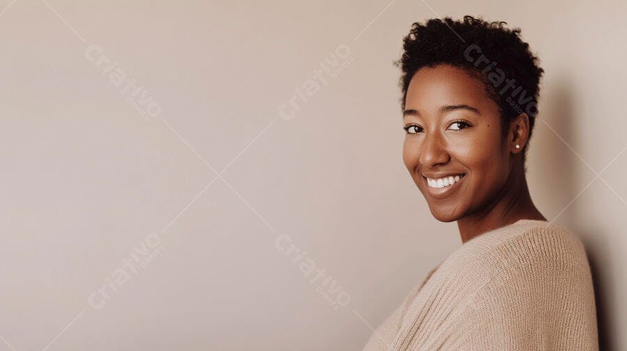 Mulher negra jovem sorrindo com suéter bege em fundo neutro