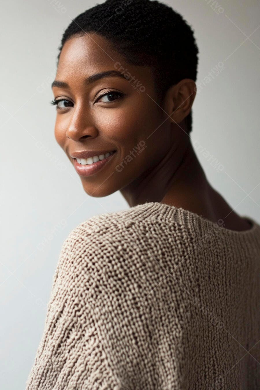 Mulher negra de cabelo curto sorrindo com suéter bege olhando por cima do ombro