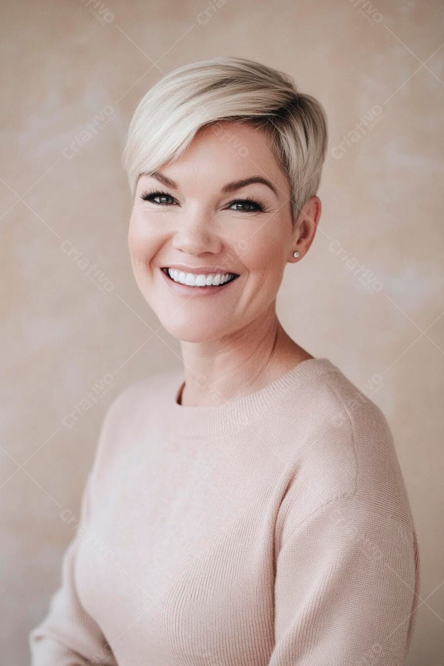 Mulher loira sorrindo com suéter rosa claro em estúdio bege