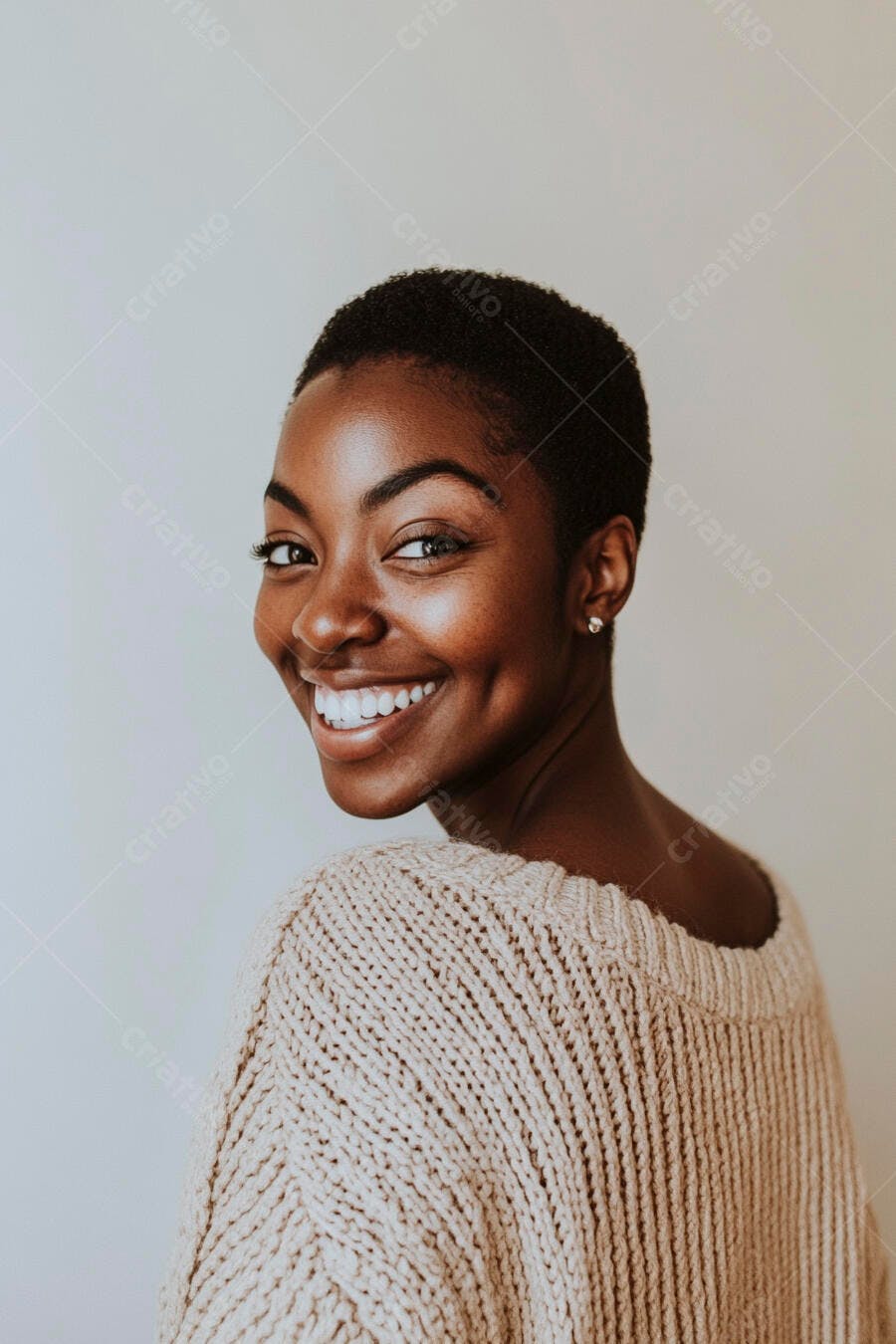 Mulher negra jovem sorrindo com suéter bege casual em estúdio claro