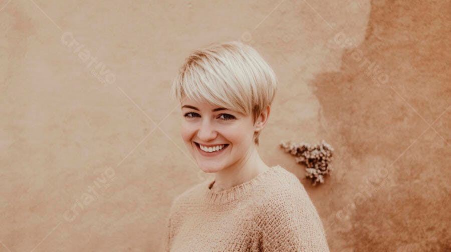 Mulher caucasiana loira de cabelo curto sorrindo com suéter bege