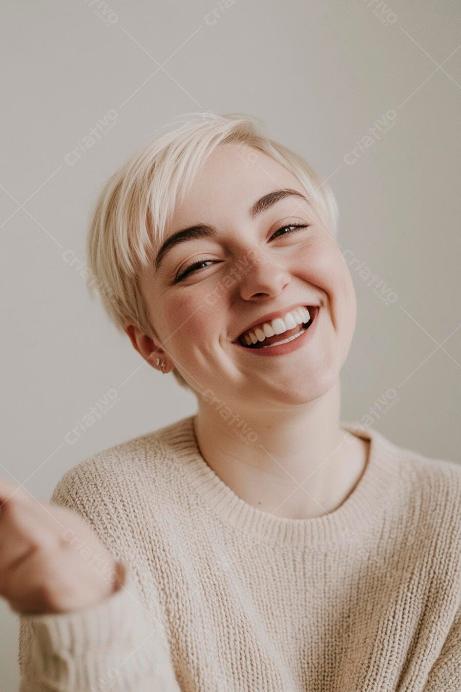 Mulher jovem loira de cabelo curto sorrindo amplamente com suéter bege