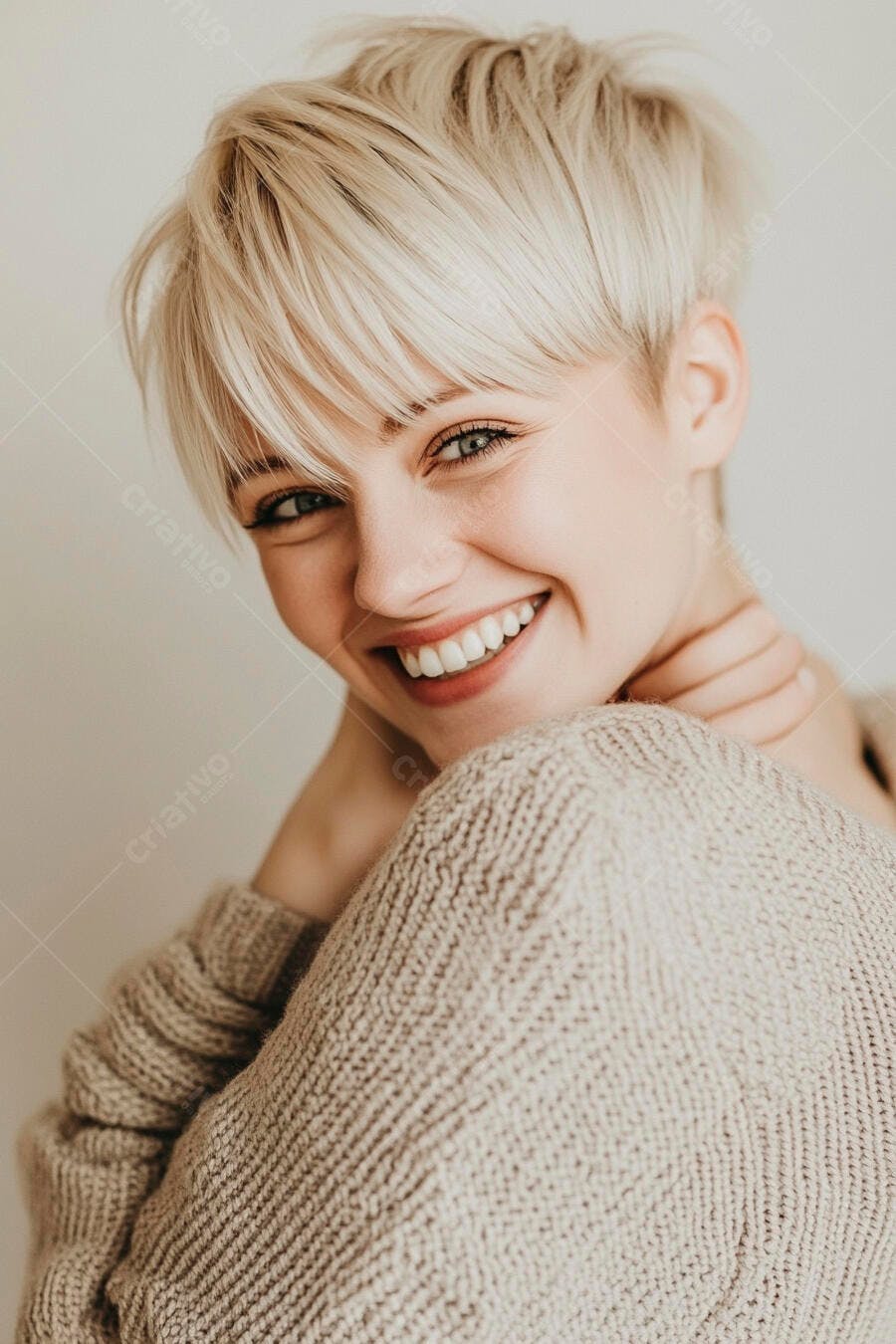 Mulher jovem loira caucasiana sorrindo com suéter bege em estúdio