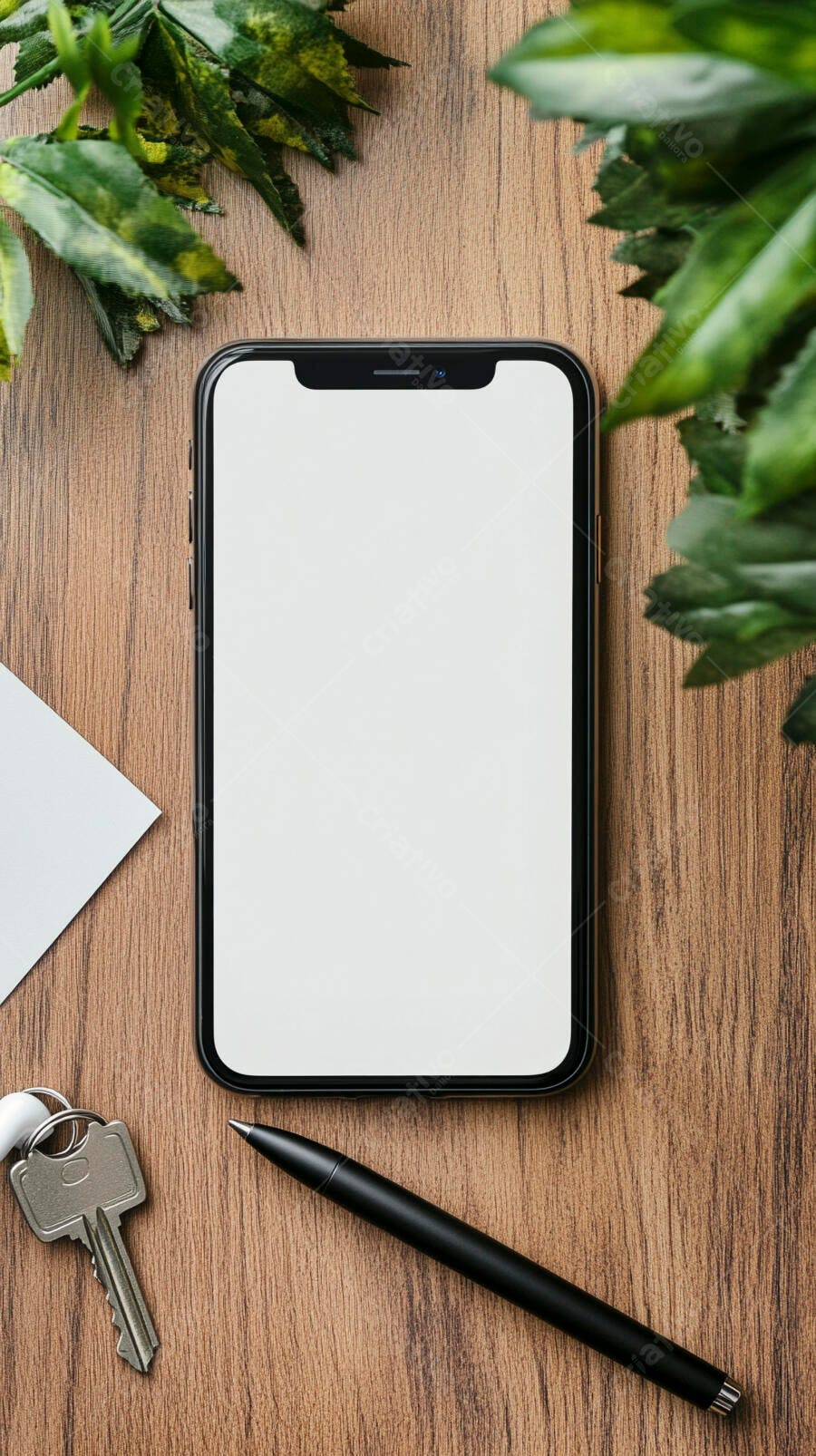 Smartphone preto com tela branca sobre mesa de madeira e folhas verdes