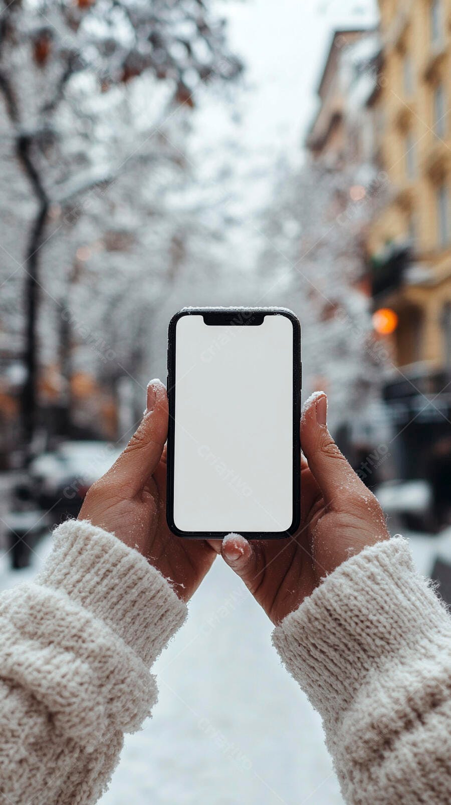 Mãos com suéter branco segurando smartphone na rua nevada inverno