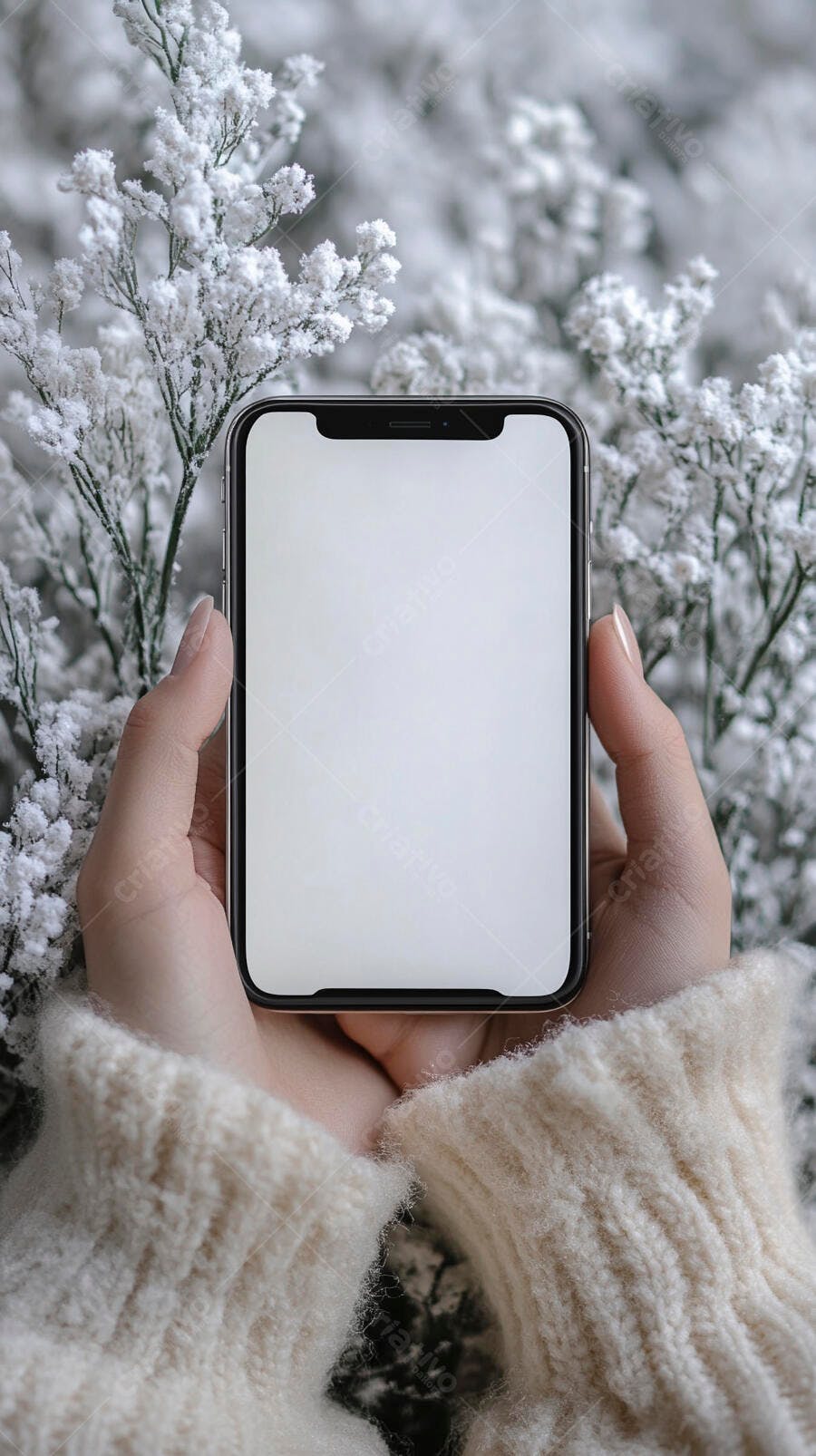 Mãos femininas em suéter creme seguram celular mockup com fundo nevado