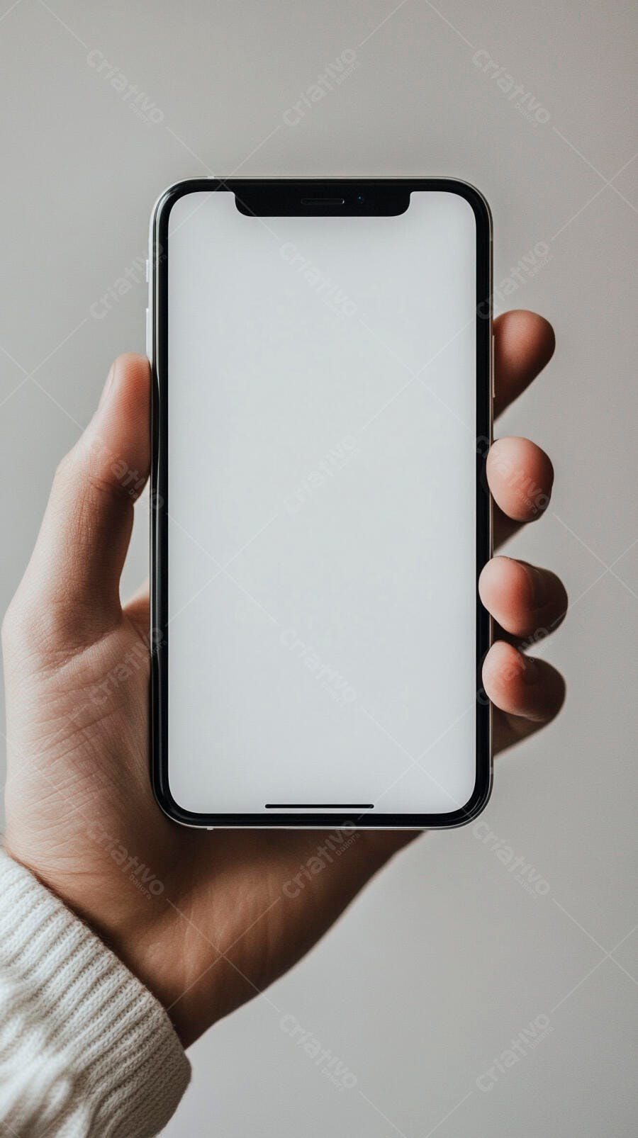 Mão segurando smartphone preto com tela branca para mockup em suéter branco