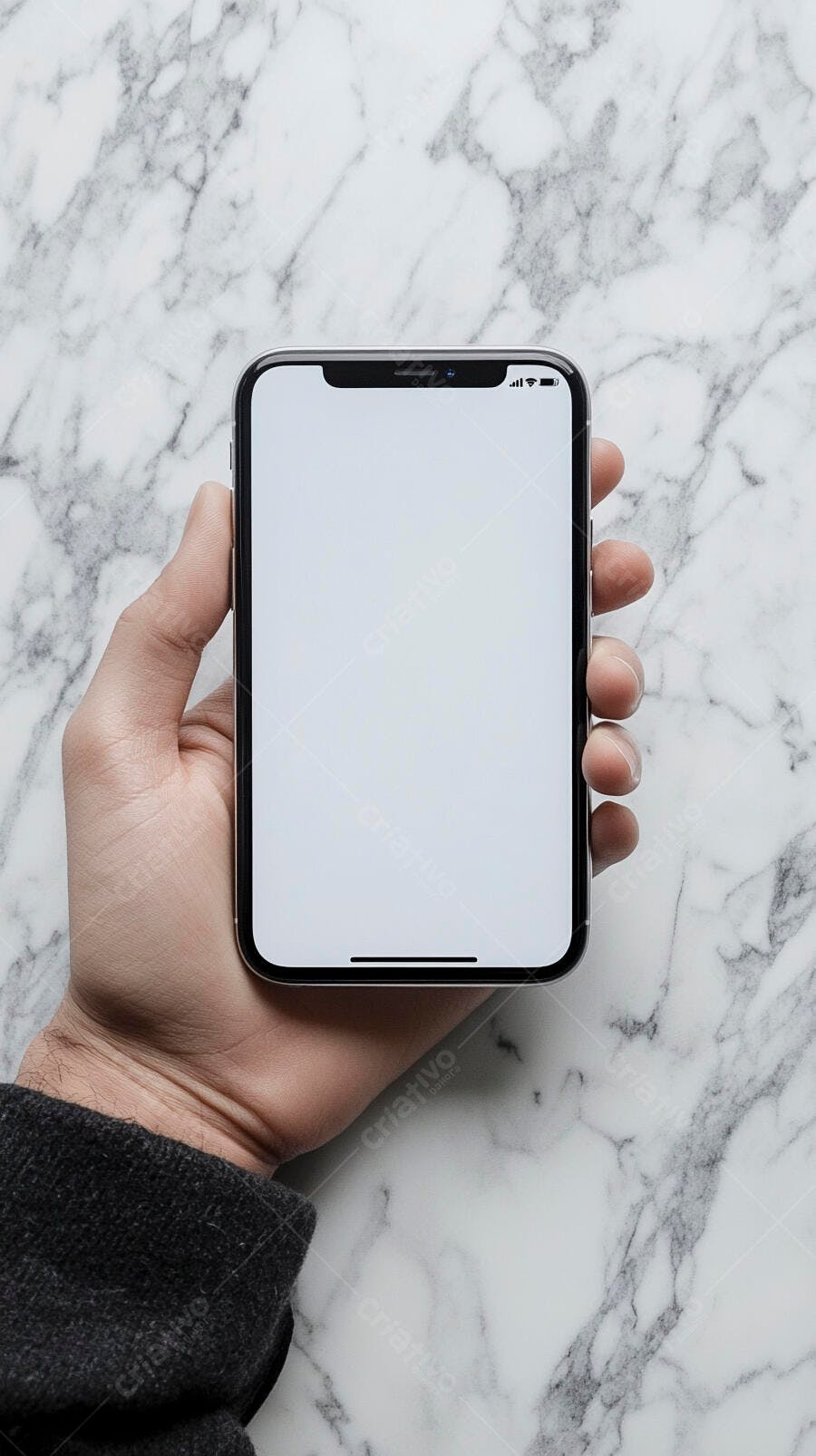 Mão segurando smartphone com tela branca sobre mármore branco