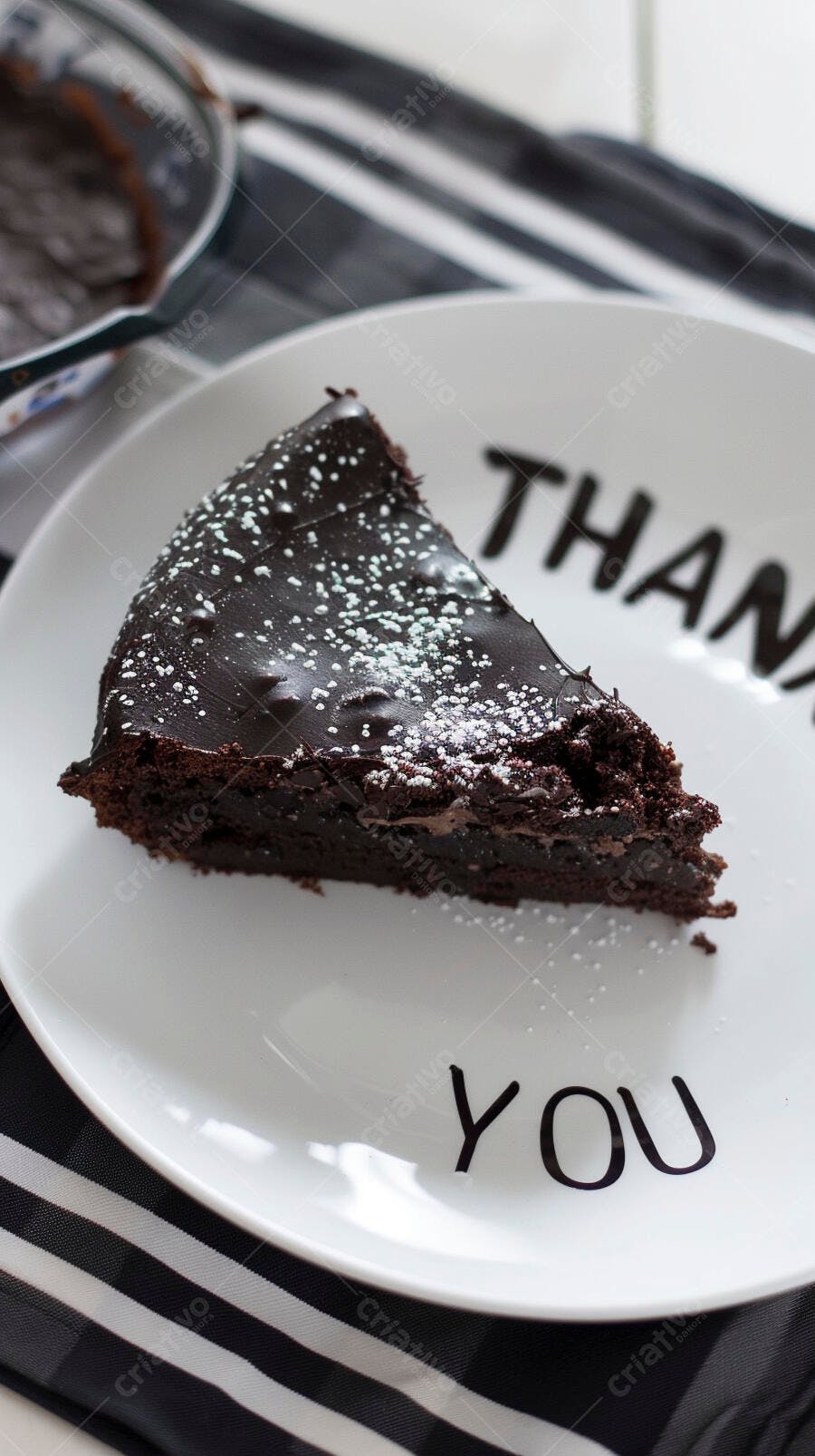 Fatia de bolo de chocolate escuro com açúcar de confeiteiro em prato branco Thank You