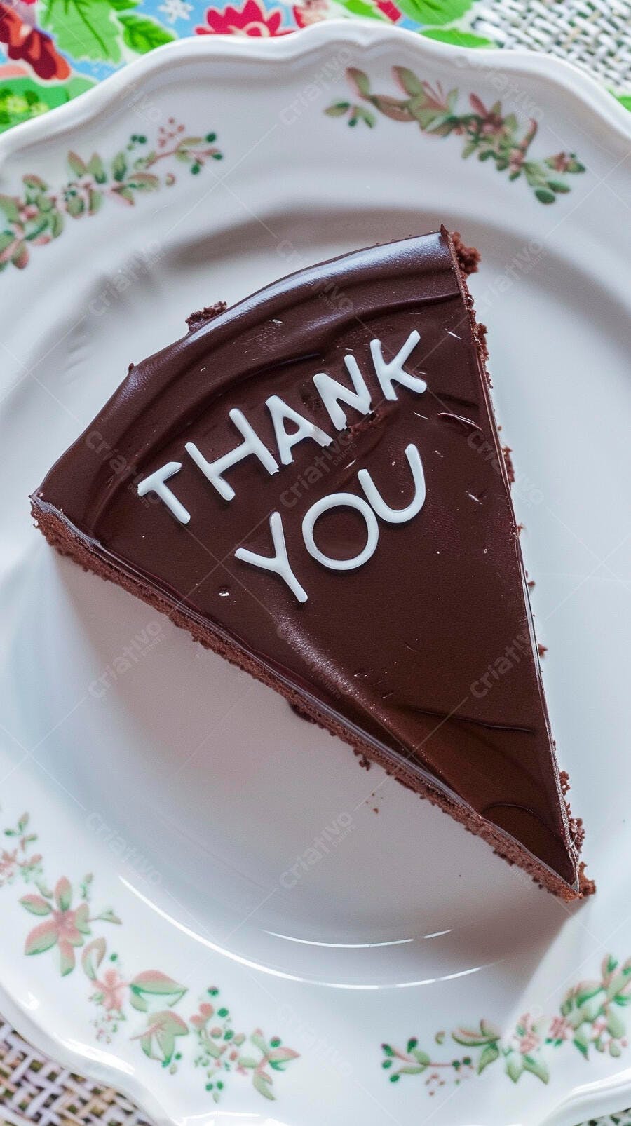 Fatia de bolo de chocolate com "Thank You" em cobertura brilhante sobre prato floral
