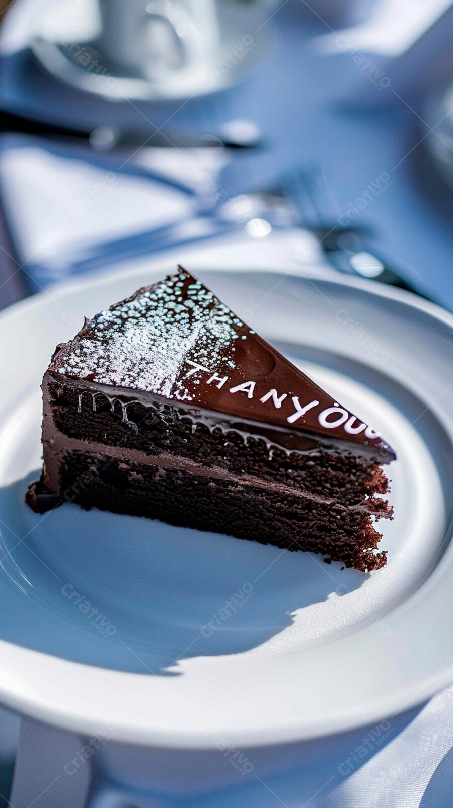 Fatia de bolo de chocolate com "THANK YOU" e açúcar em pó em prato branco