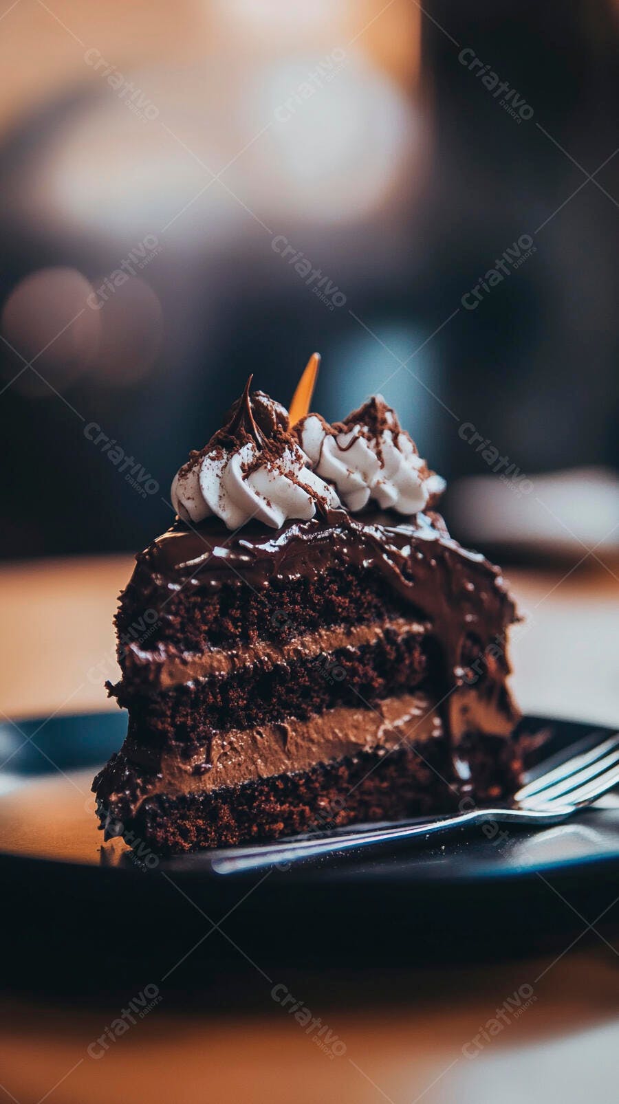 Fatia de bolo de chocolate com camadas e chantilly em prato escuro