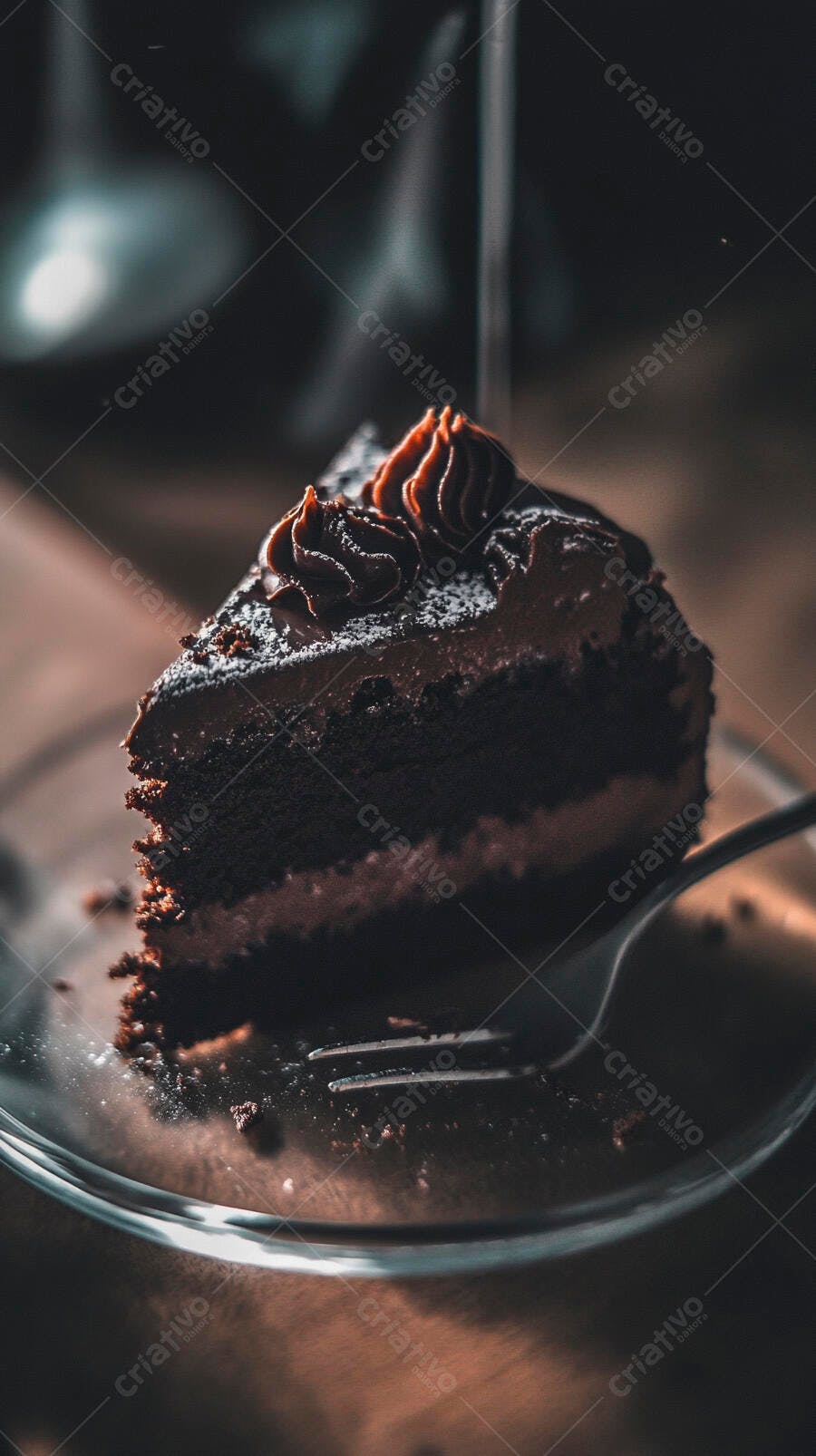 Fatia de bolo de chocolate com cobertura e açúcar em prato de vidro