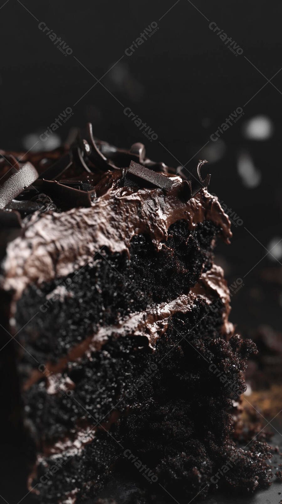 Fatia de bolo de chocolate cremoso com raspas sobre fundo escuro