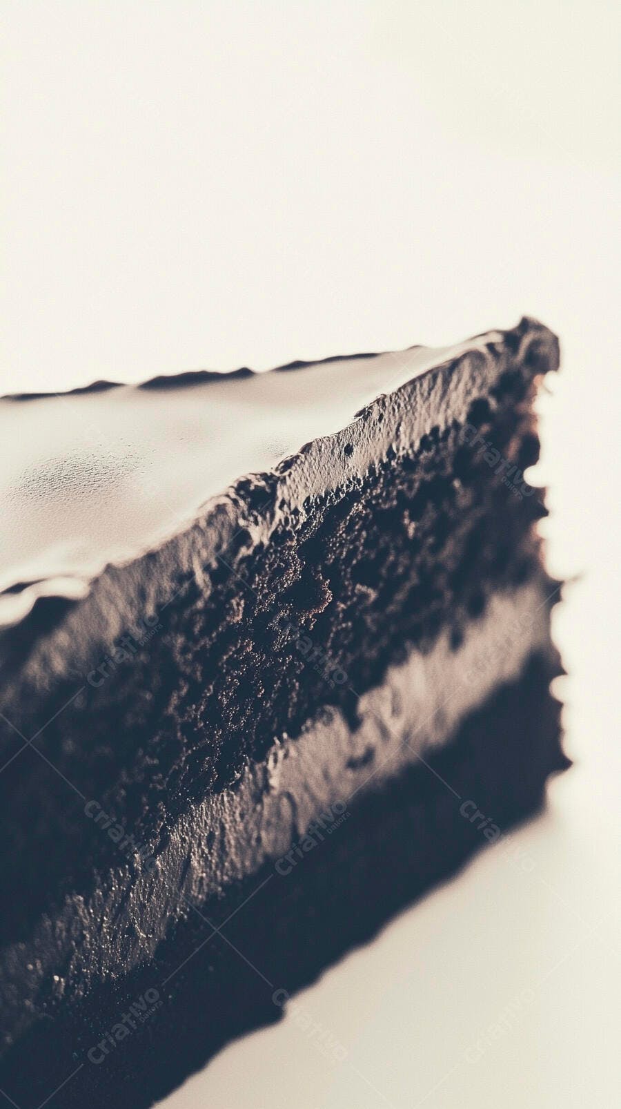 Fatia de bolo de chocolate com cobertura cremosa em fundo claro