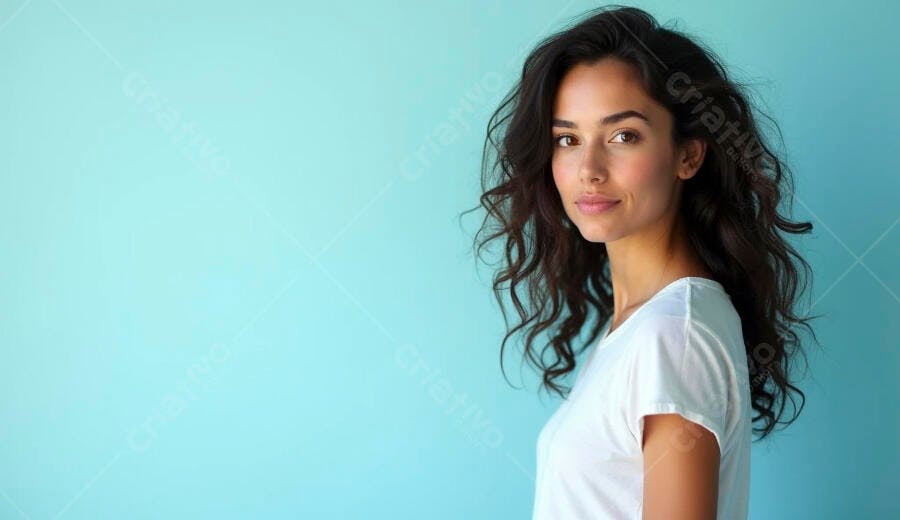 Mulher jovem de cabelos escuros sorrindo em camiseta branca fundo azul claro