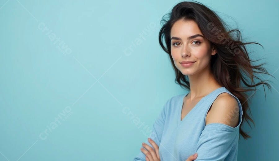 Mulher jovem morena sorrindo com braços cruzados em fundo azul