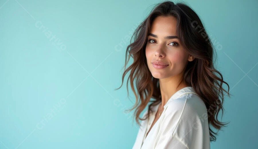 Mulher jovem morena sorrindo gentilmente com cabelo castanho e fundo azul turquesa