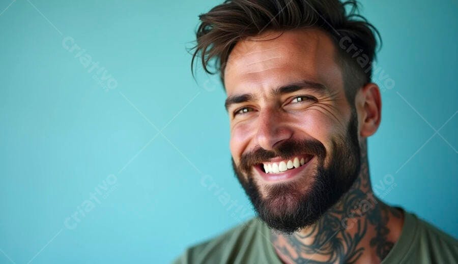 Homem barbudo tatuado sorrindo feliz em fundo azul turquesa