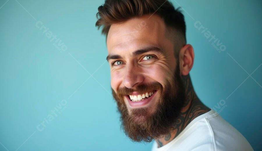 Homem barbudo tatuado sorrindo feliz contra fundo azul turquesa