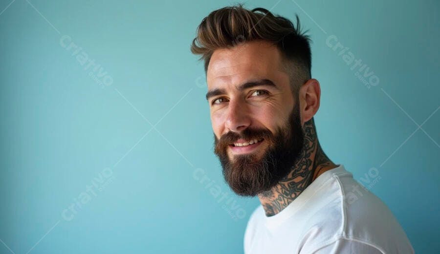 Homem sorrindo com barba e tatuagens no pescoço sobre fundo azul-claro