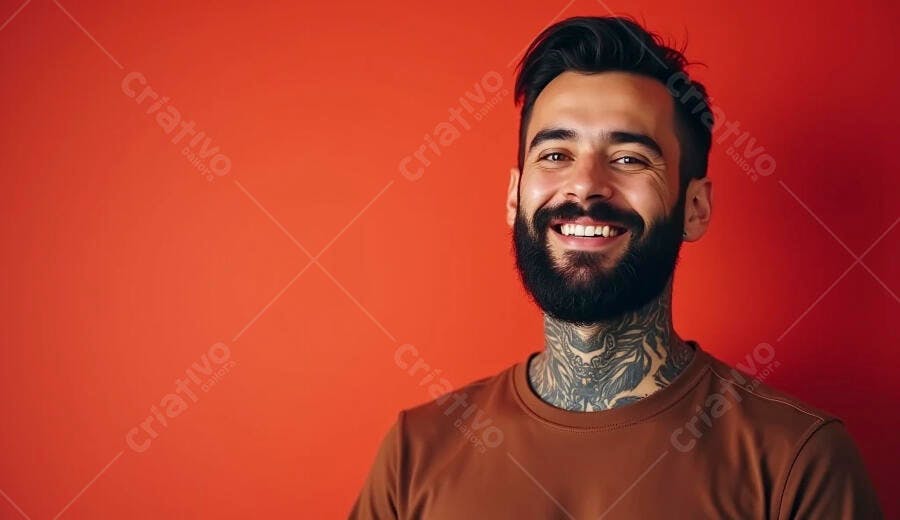 Homem sorrindo com barba e tatuagens no pescoço sobre fundo vermelho