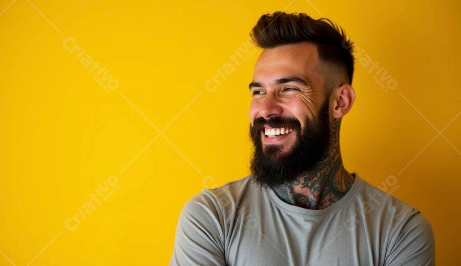 Homem barbudo tatuado sorrindo feliz contra fundo amarelo vibrante