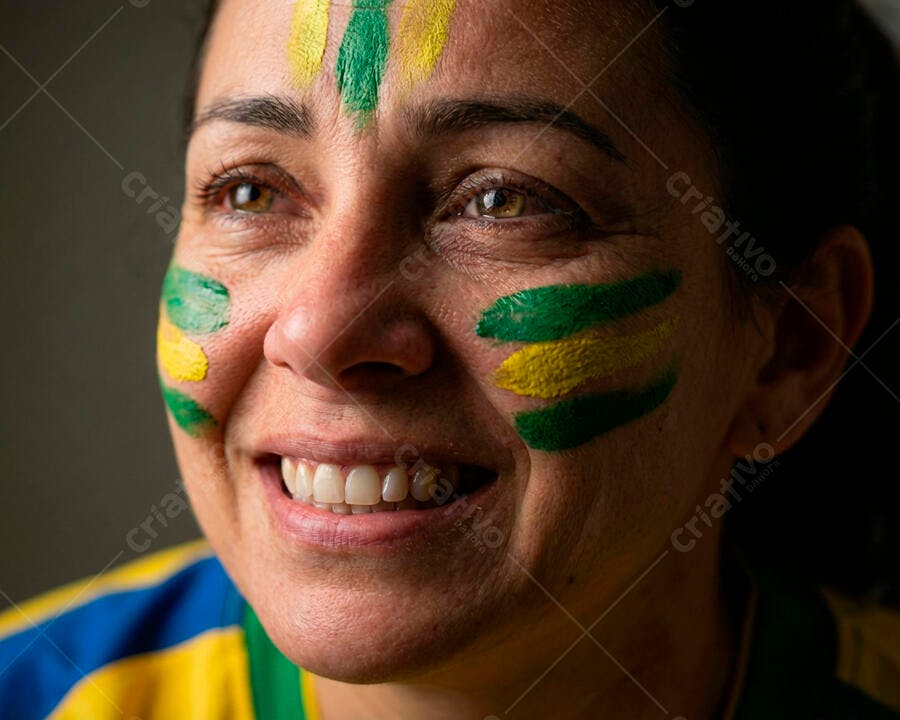 Mulher torcedora brasileira sorrindo com rosto pintado verde e amarelo