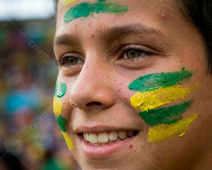 Menino torcedor com rosto pintado de verde e amarelo sorrindo em evento esportivo