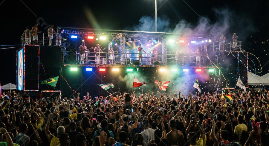 Pessoas festejam em show de trio elétrico noturno com luzes coloridas e confetes